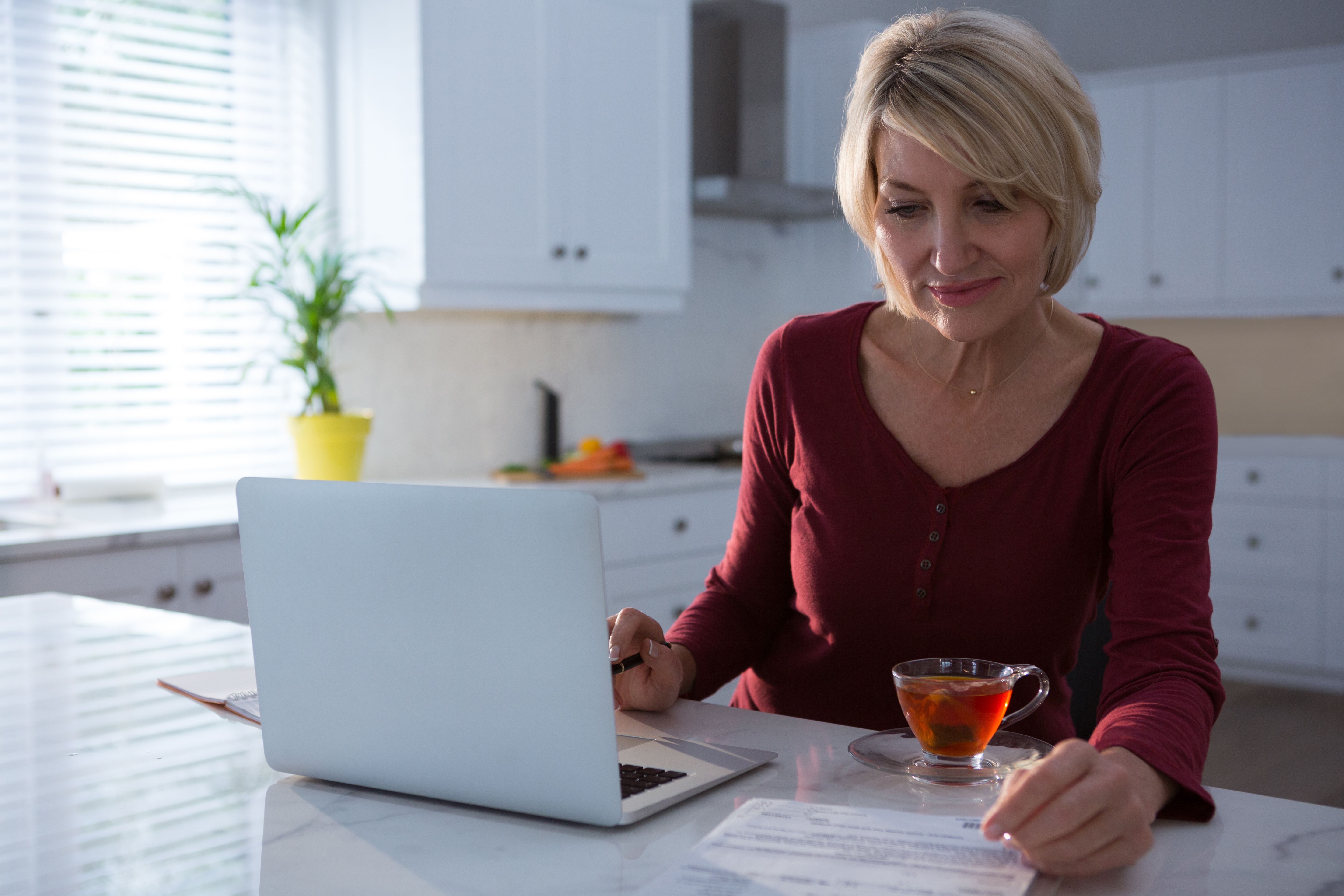 person working remotely from home in kitchen with laptop