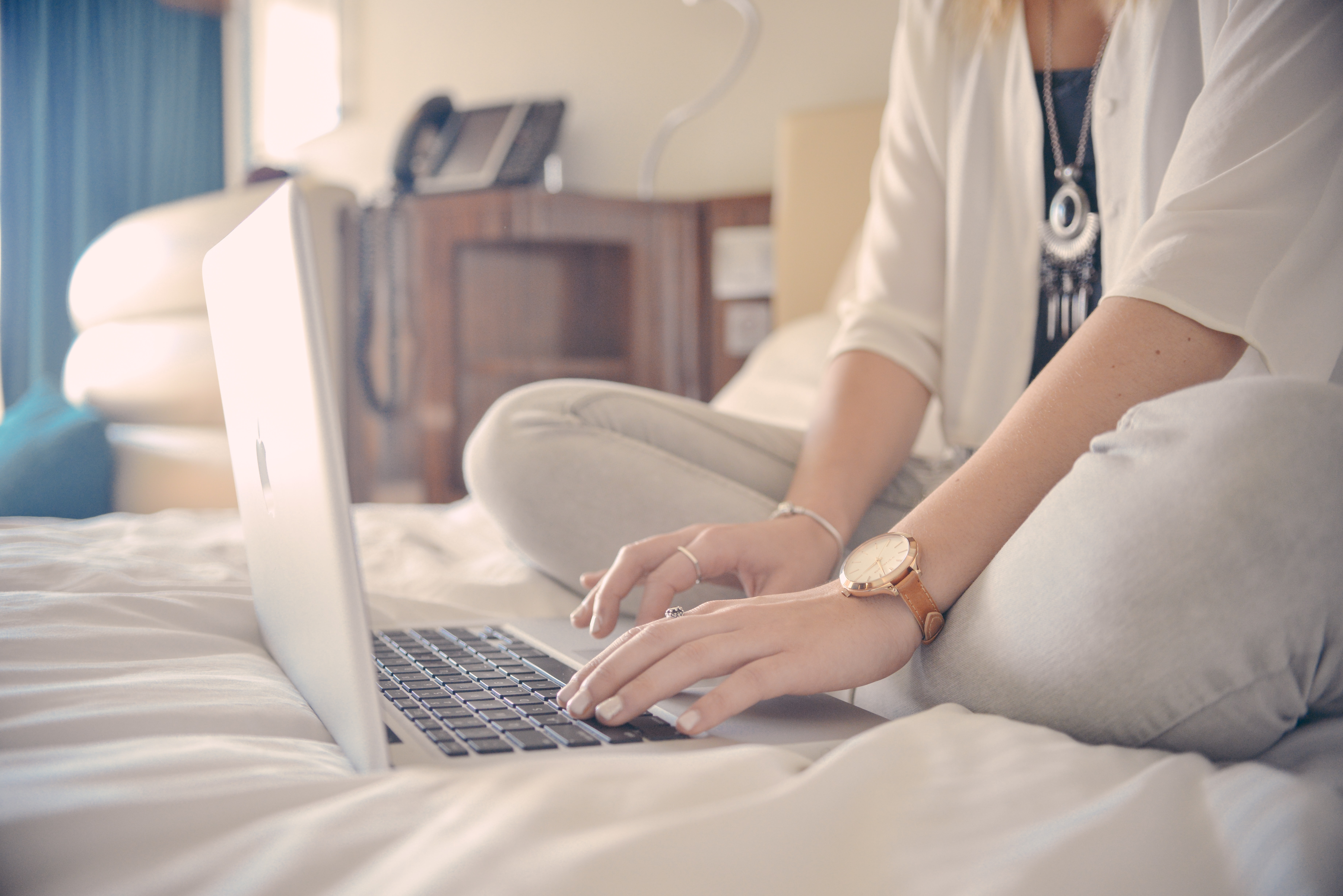 person working remotely from home with laptop on bed